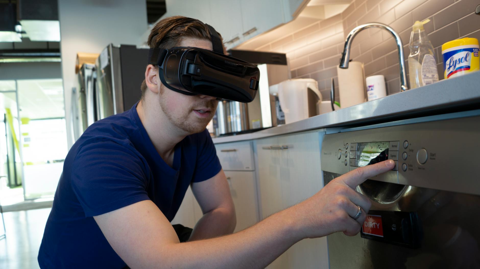 Man interacts with kitchen appliance using virtual reality headset.