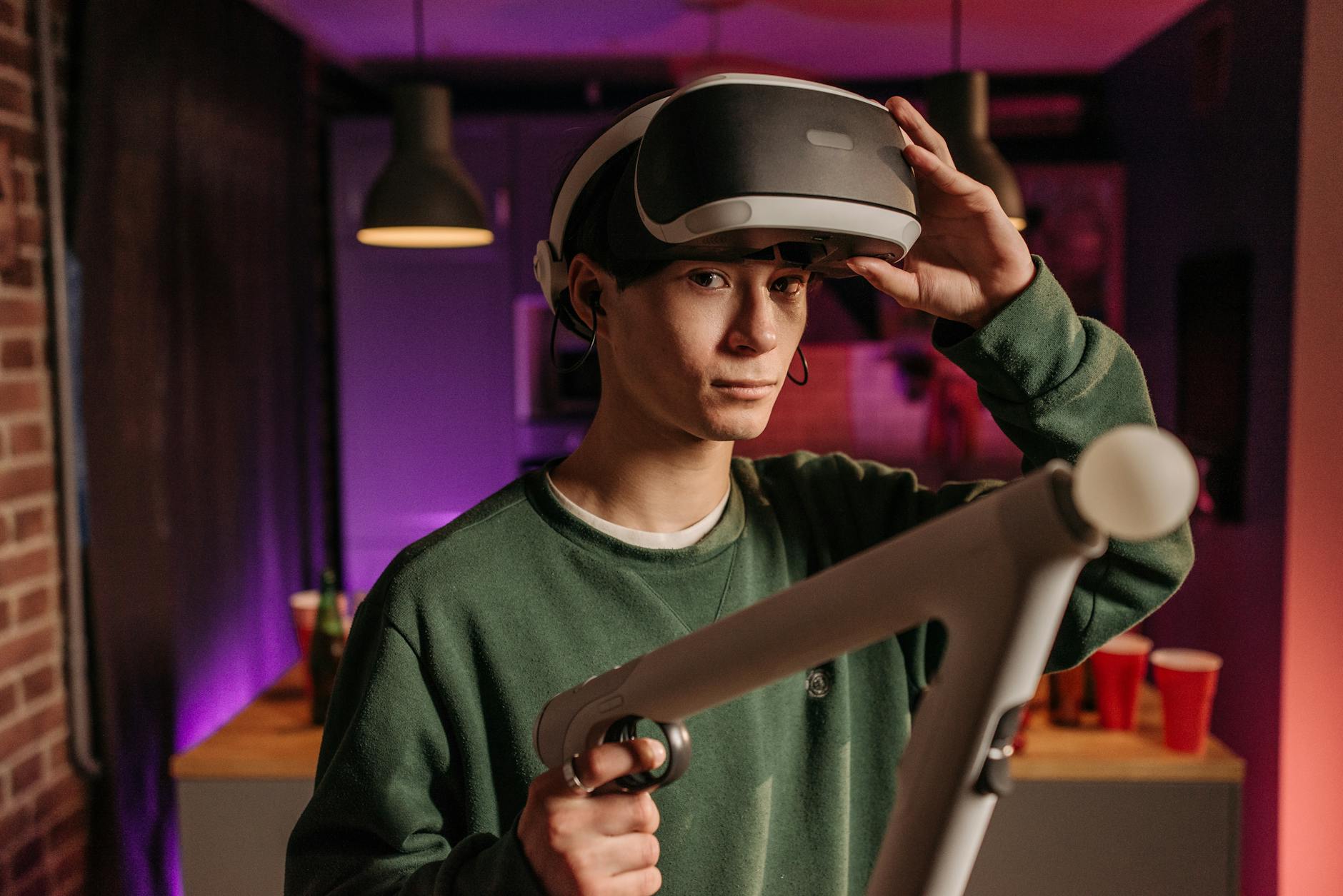 A young man explores virtual reality gaming with a headset and controllers in a cozy indoor setting.